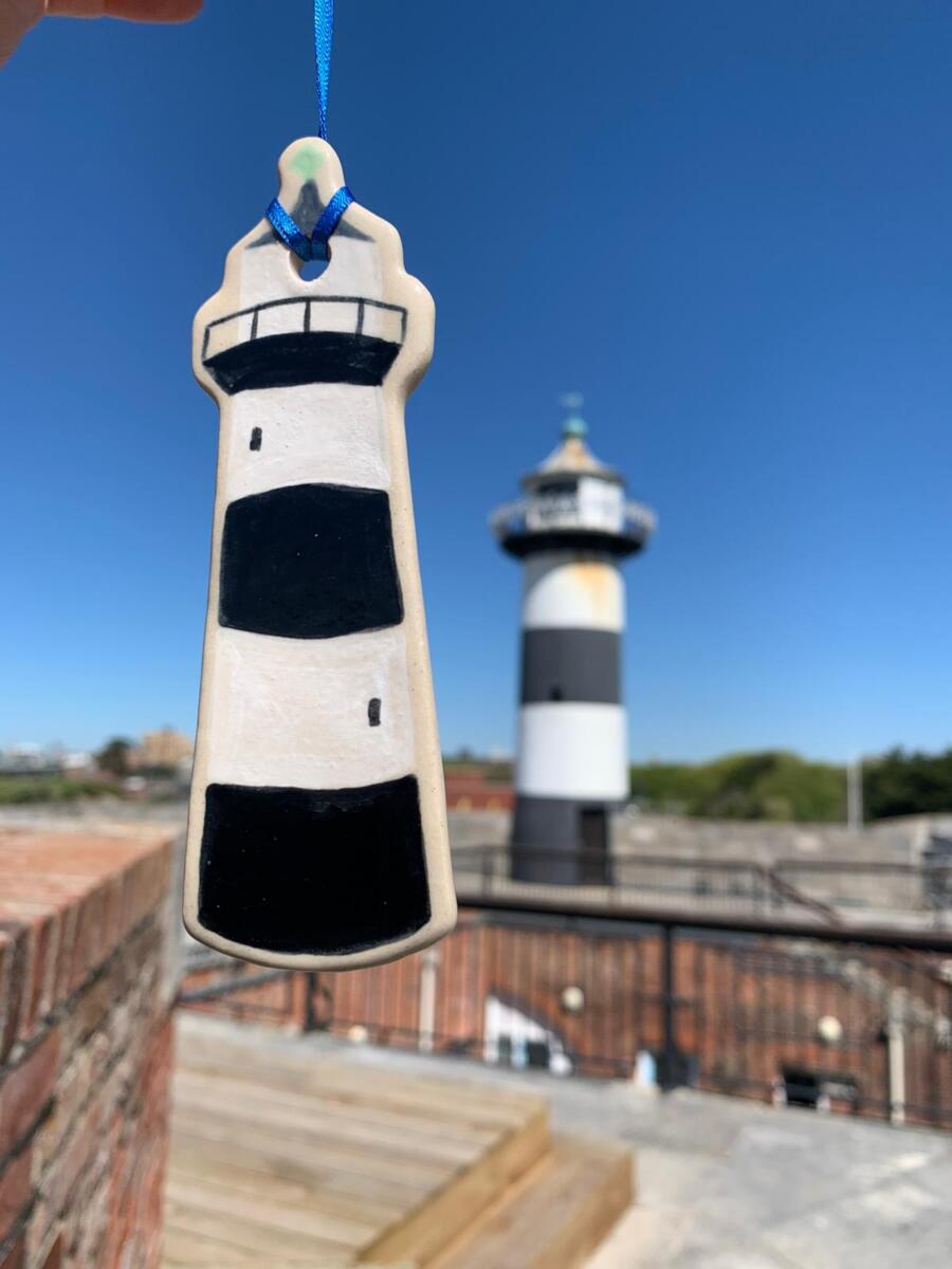 Handmade ceramic piece of  lighthouse held out in front of Southsea Castle
